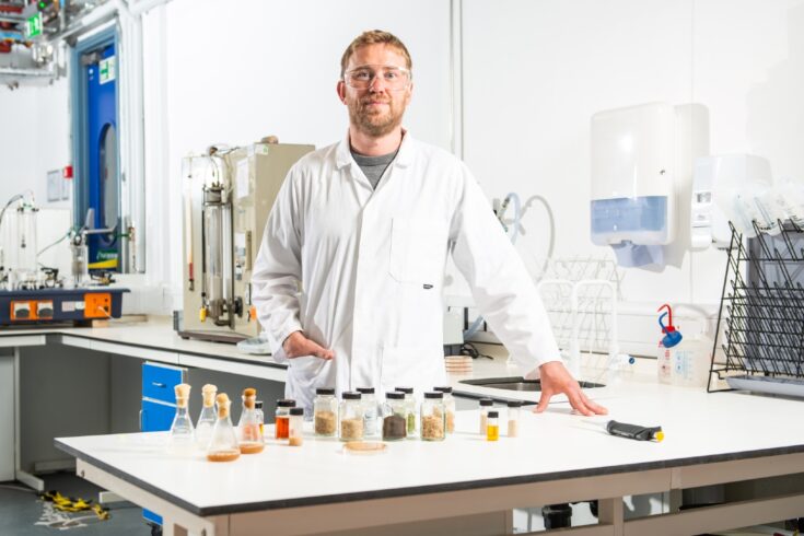 Professor Chris Chuck stands in his lab with samples of feedstock.
