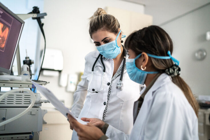 Two female doctors discussing some exams together at the hospital.