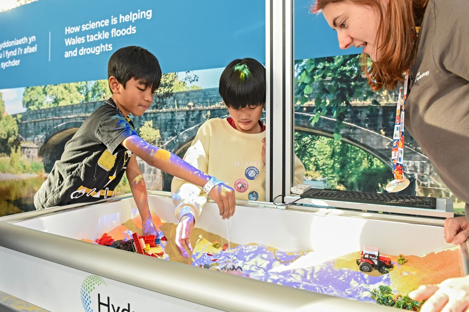 Two children and presenter at an exhibit stand.