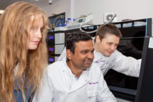 Dr Anna Lindell, Dr Kiran Patil and Dr Sonja Blasche gathered around a monitor in the MRC Toxicology Unit laboratory.