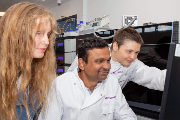 Dr Anna Lindell, Dr Kiran Patil and Dr Sonja Blasche gathered around a monitor in the MRC Toxicology Unit laboratory.