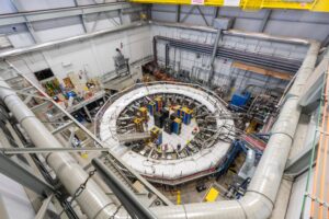 Seen from above, a large room filled with technical equipment, and a scientist at work in the middle.