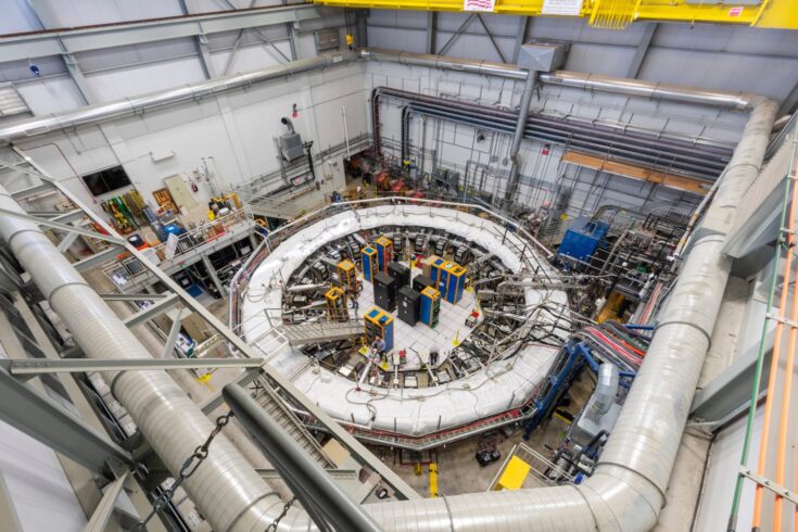 Seen from above, a large room filled with technical equipment, and a scientist at work in the middle.