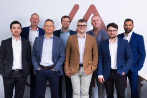 Aeramine team posing for photo against logo backdrop.