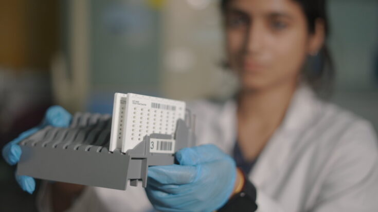 Lab technician holding up diagnostics testing device.