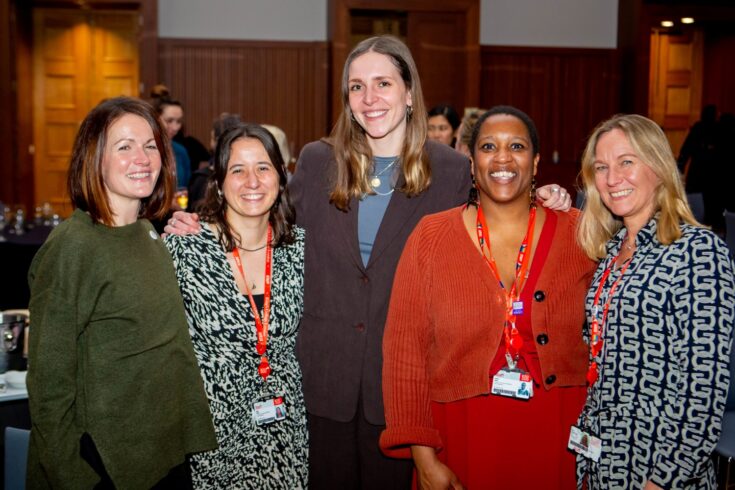 Five people standing and smiling