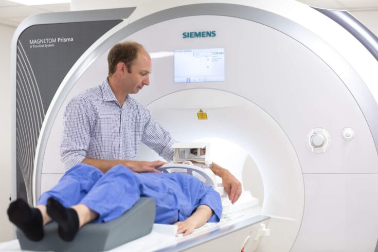 Doctor assisting patient as an MRI scan is performed.
