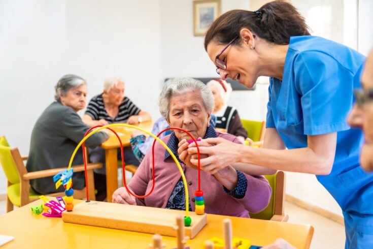 Older woman and caregiver playing skill board games in a nursing home.