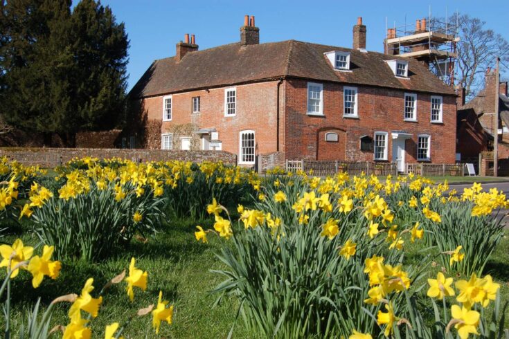 Jane Austen's home in Chawton, Hampshire behind a garden of daffodils.