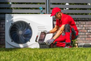 Technician kneeling by a heat pump