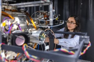 A female researcher using a complicated piece of equipment with visible wires.