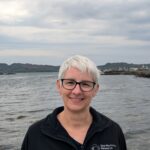 A headshot of Carol Sparling, Head of the Sea Mammal Research Unit, standing in front of the sea