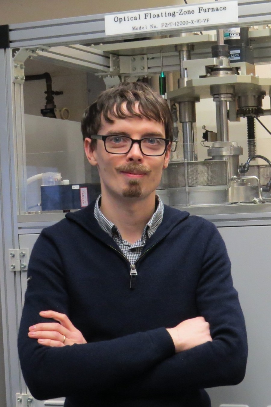 A man with glasses stood in front of a machine.