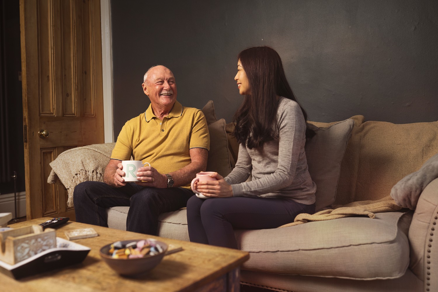 A man and a woman sat on a sofa talking.
