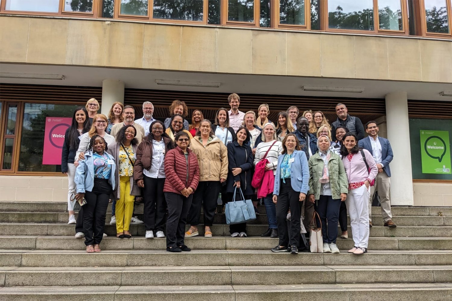 A group of adults assembled on steps in front of a building for a conference group shot