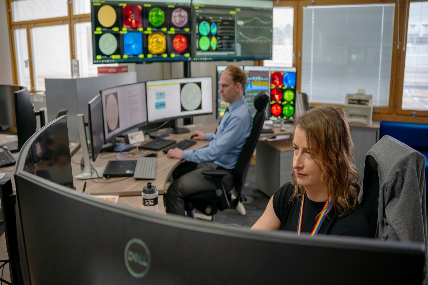 A woman and a man sat at a desk working on computers