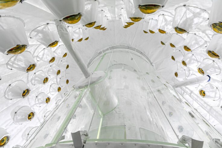 a view upward into a large white chamber with walls studded by equipment.