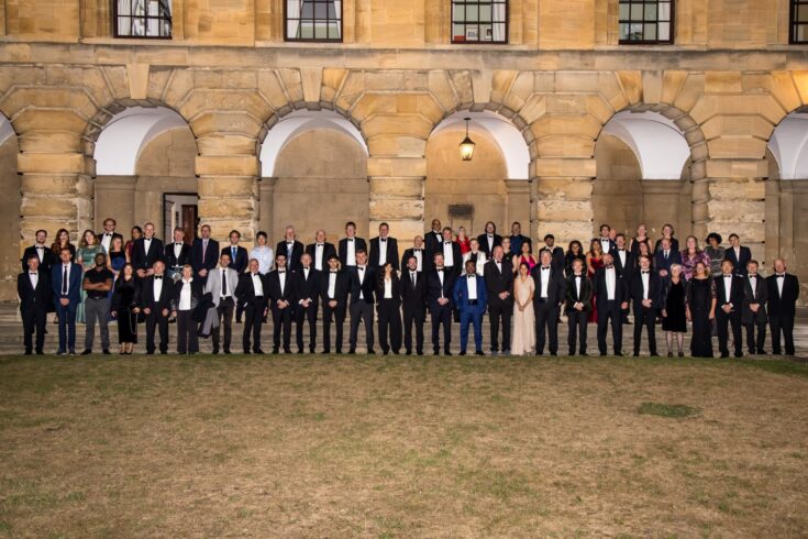 A large group of smartly dressed people standing in front of a building.