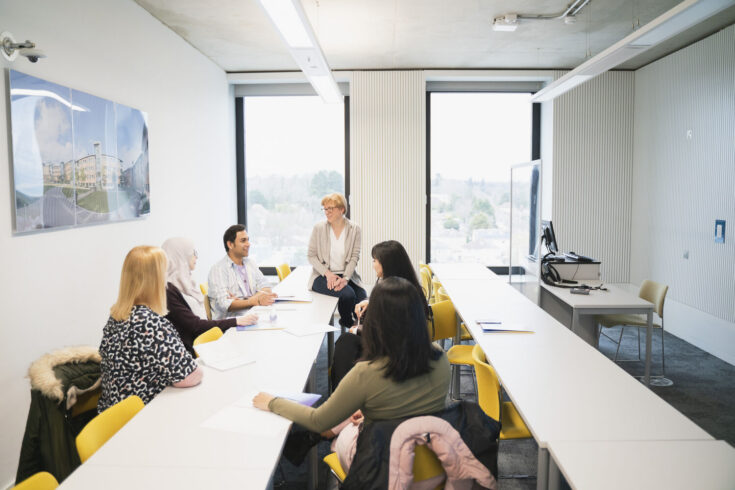 A group of researchers sat around desks in a meeting room.
